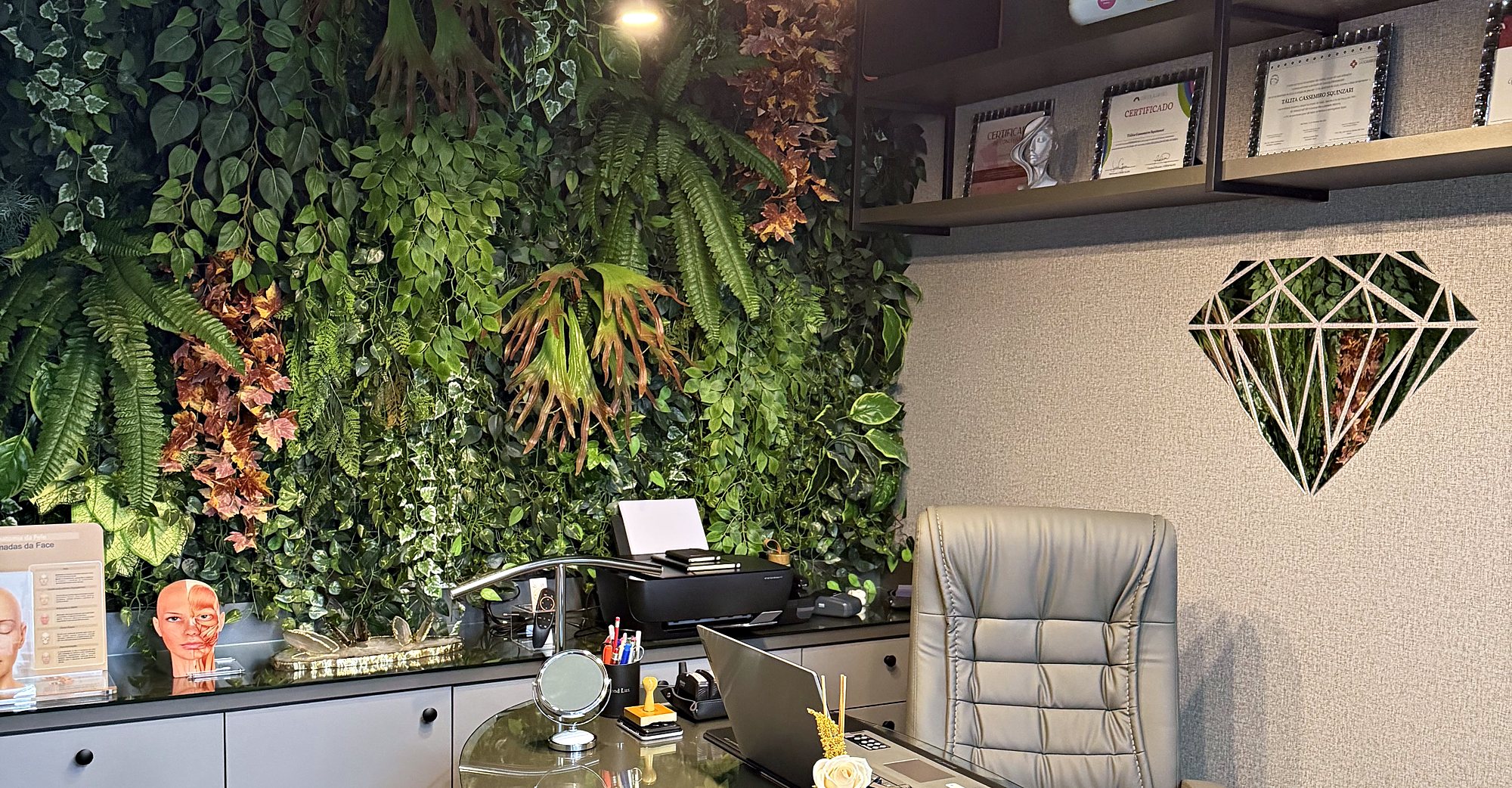 Escritório da Clínica Diamond Lux, com jardim vertical e mesa de vidro.